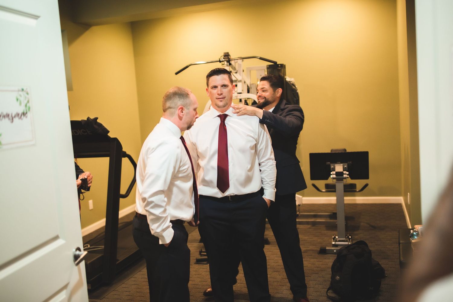 Group of formally dressed people gather in a room while getting ready.