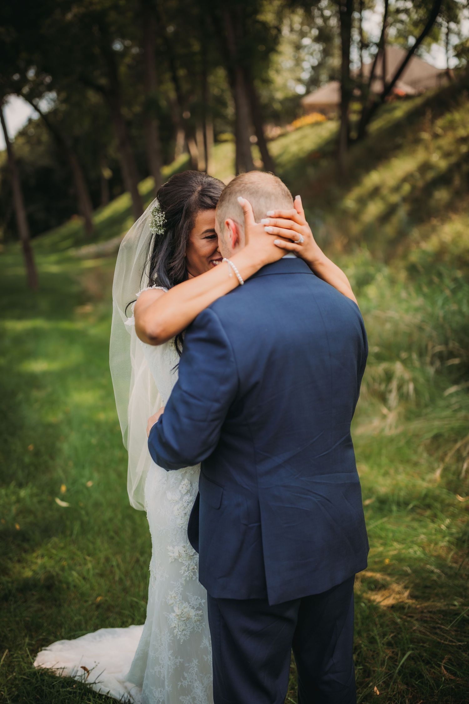 Intimate embrace between newlyweds on a wooded hillside.