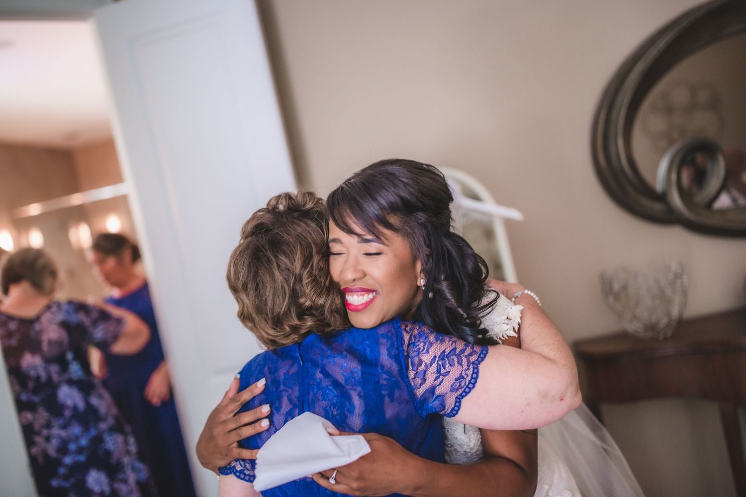 Bridesmaids in royal blue dresses share emotional moments during wedding preparations.