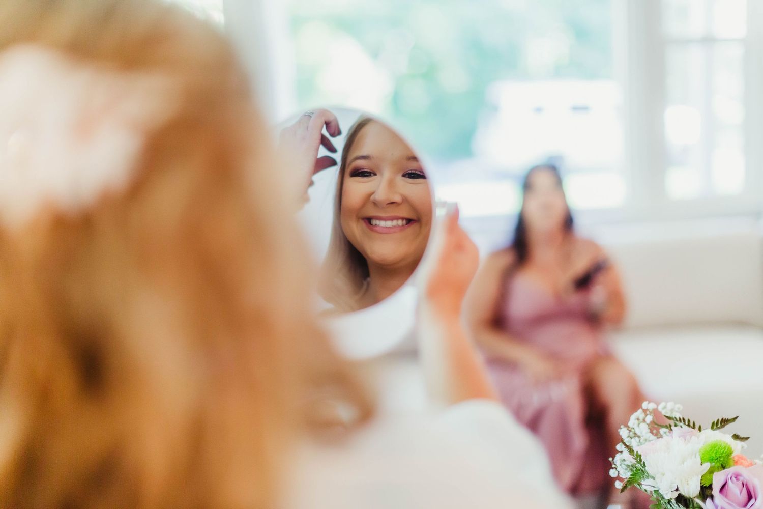 Reflection in mirror showing joyful expression during bridal preparations.