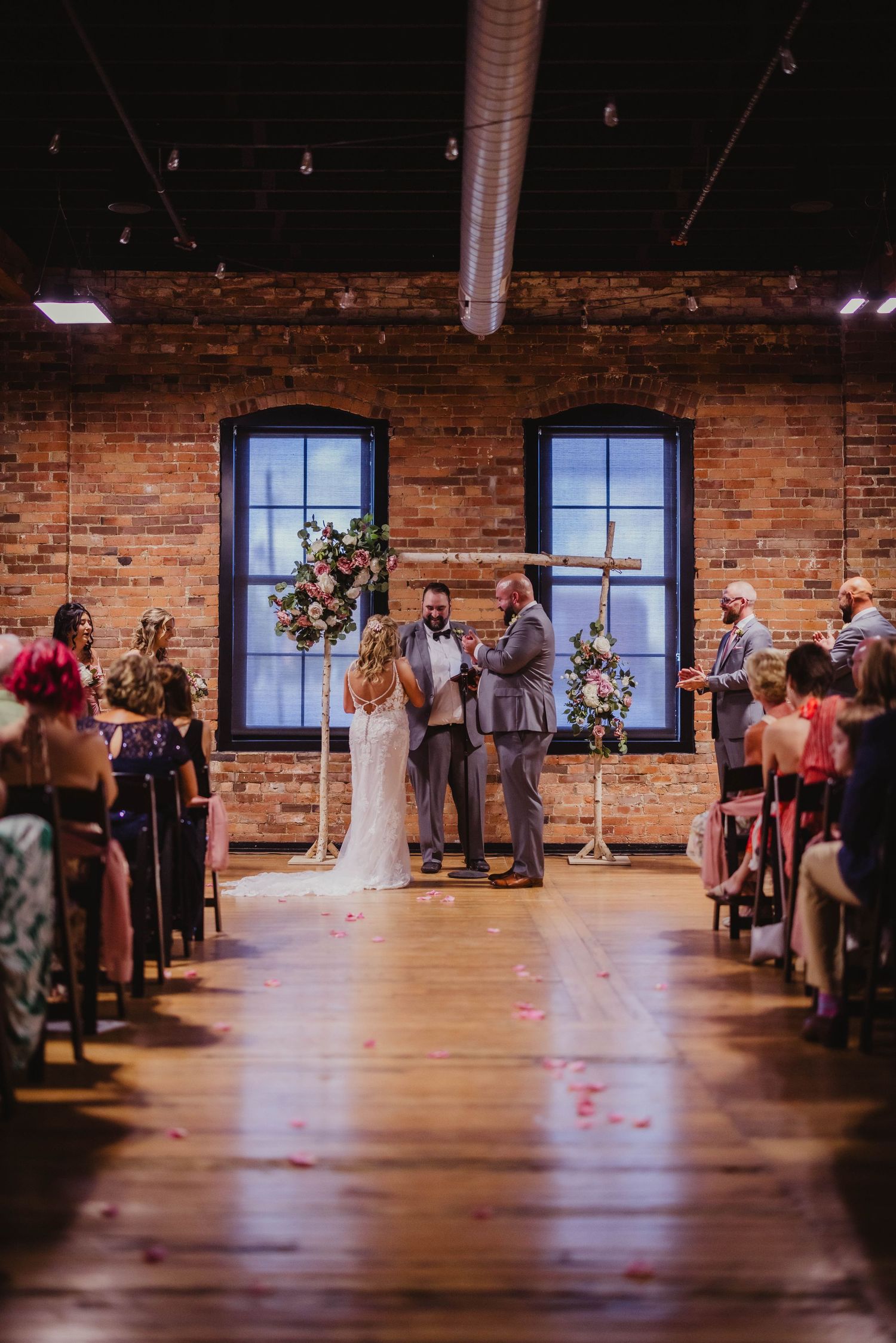 Wedding ceremony in industrial space with exposed brick walls and wooden floors.
