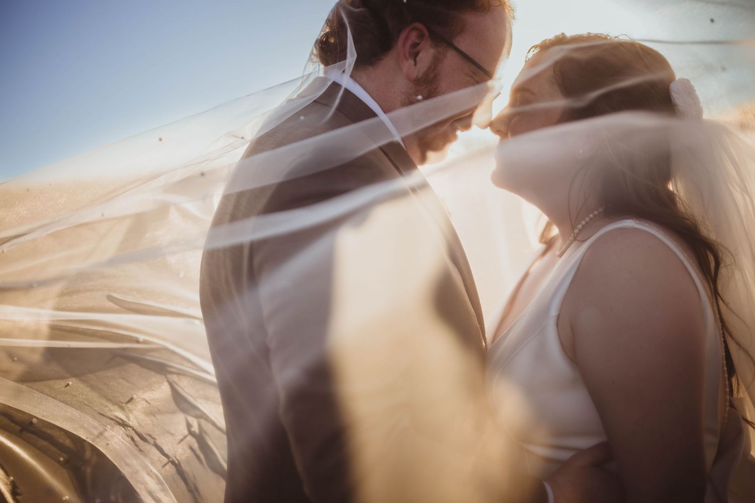 Ethereal wedding photographs showing intimate moments through flowing white fabric.
