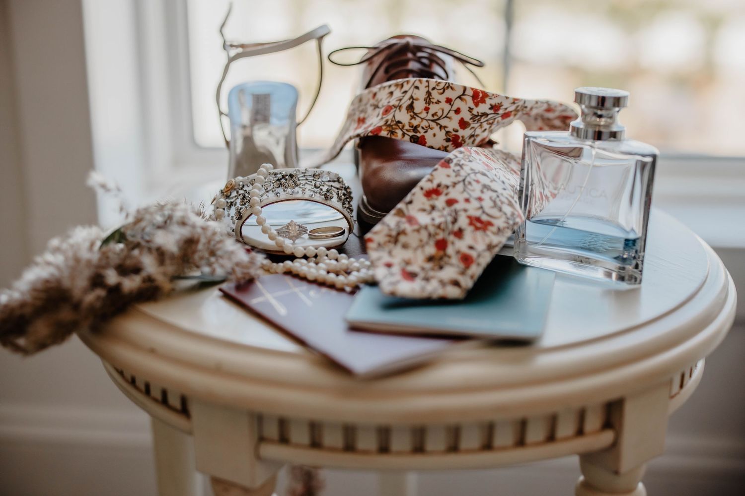 Wedding details including perfume, jewelry, and accessories arranged on an ornate white table.