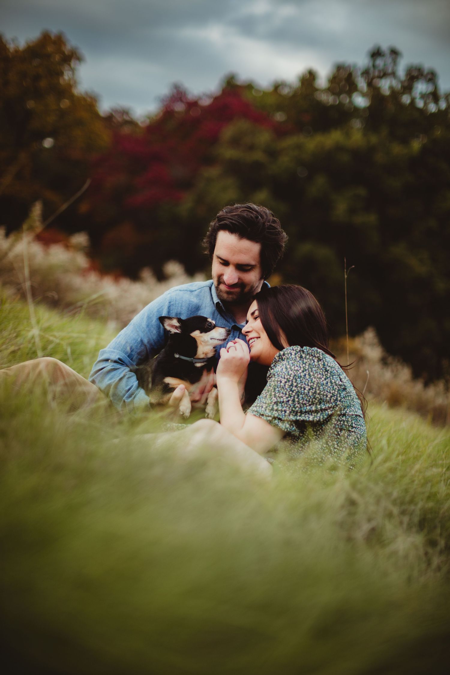 Two photographers laying in grass field taking pictures of each other.