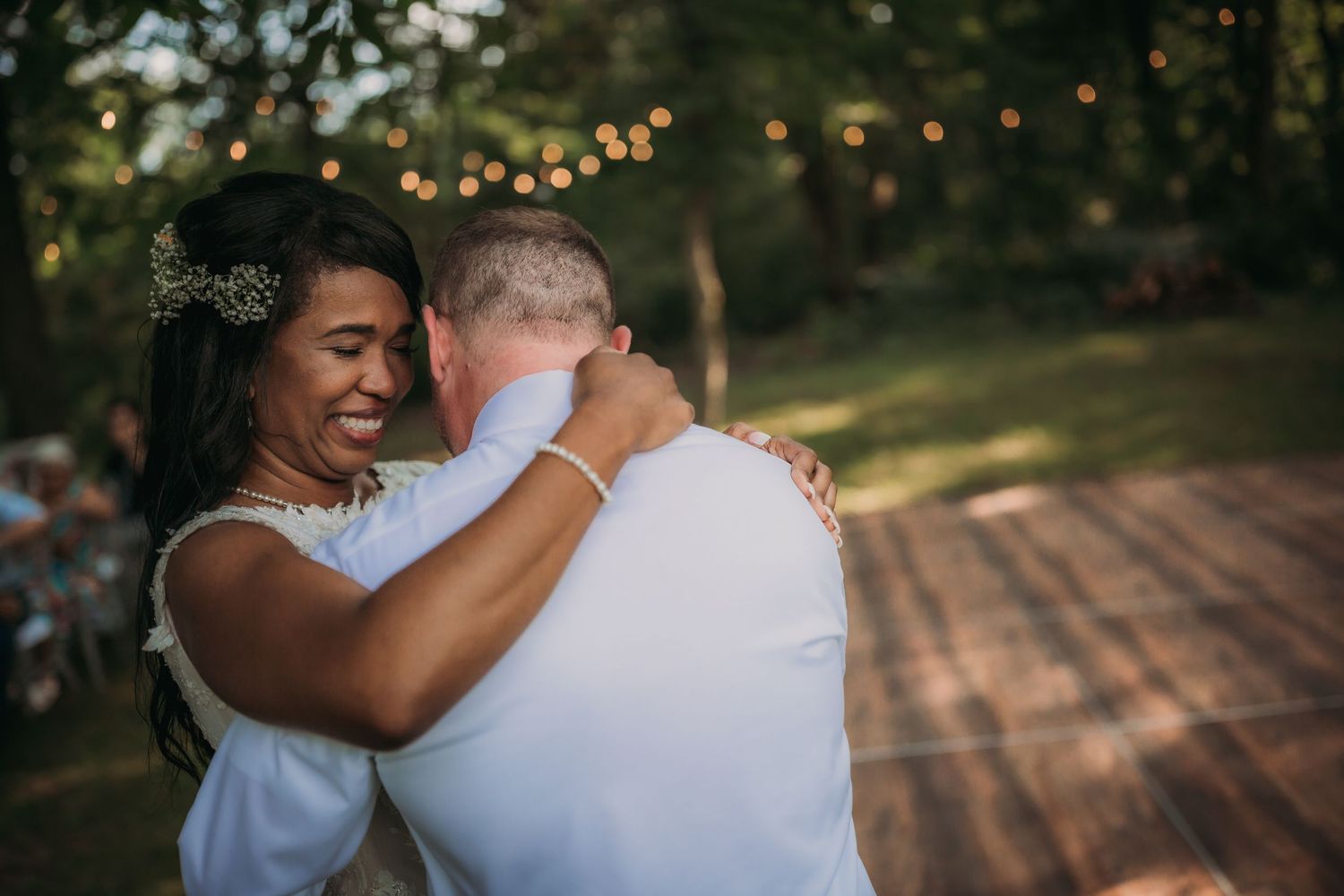 Intimate dance moment captured at outdoor wedding with string lights and natural scenery.