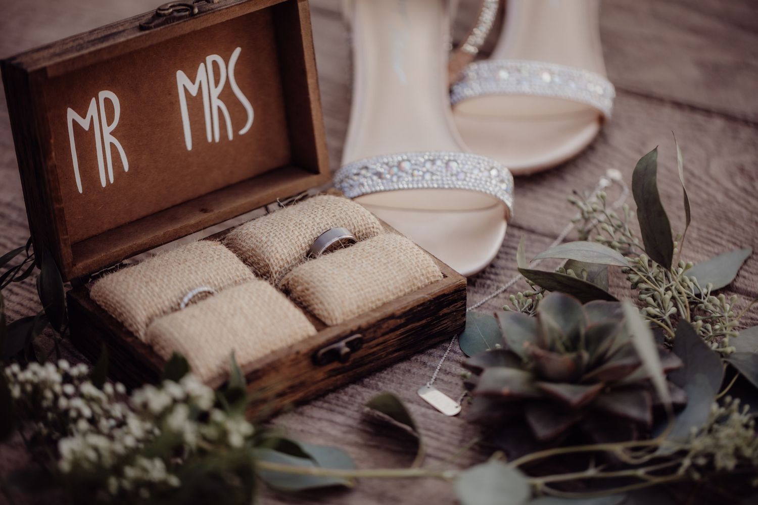 Rustic wooden ring box labeled 'Mr Mrs' with wedding rings and bridal shoes.