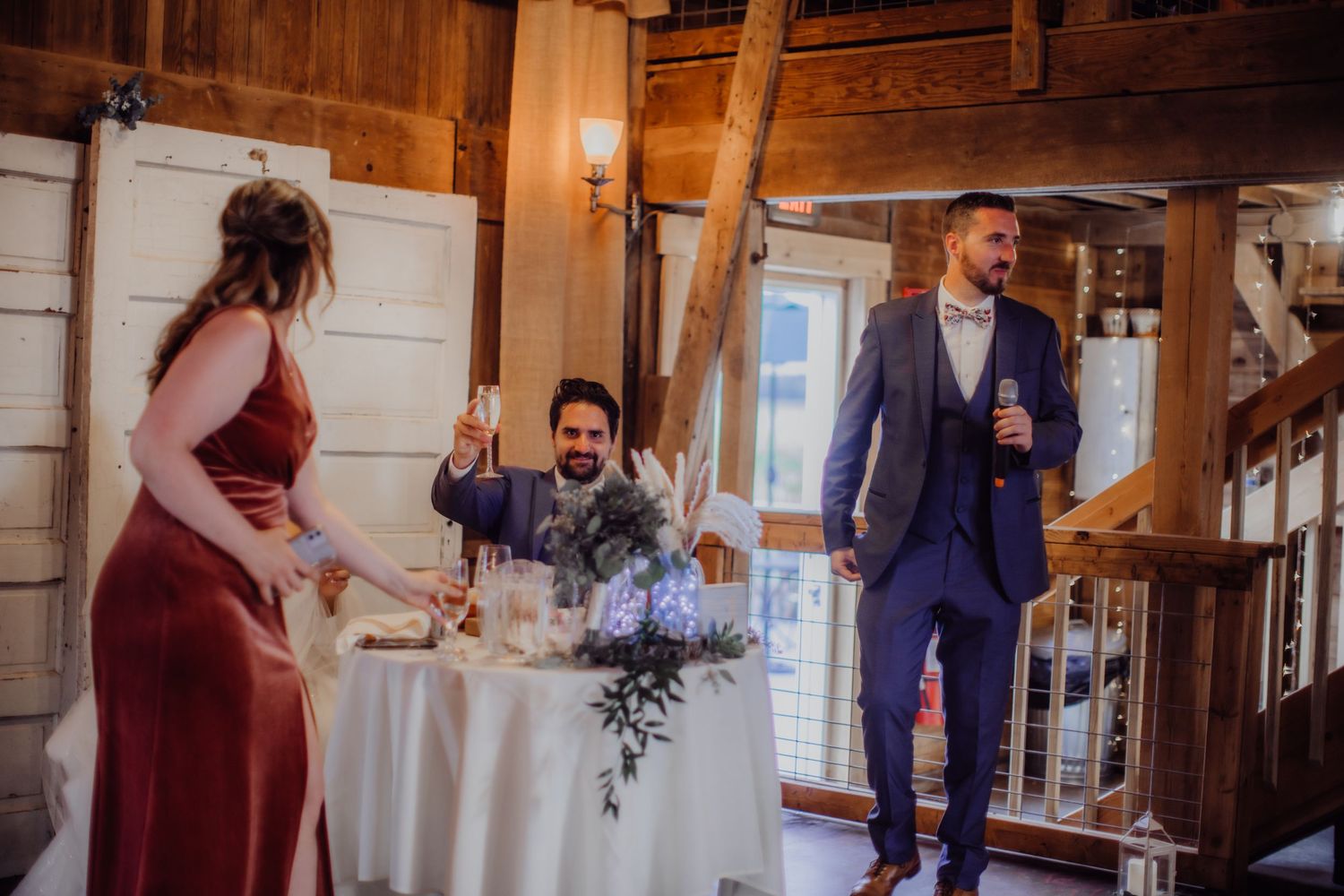 Wedding reception in a rustic barn venue with wooden walls and elegant table settings.