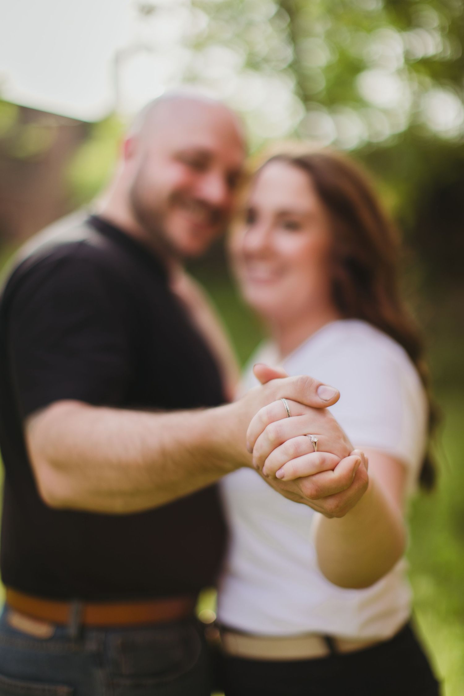 Romantic couple dancing and holding hands during outdoor engagement photoshoot.