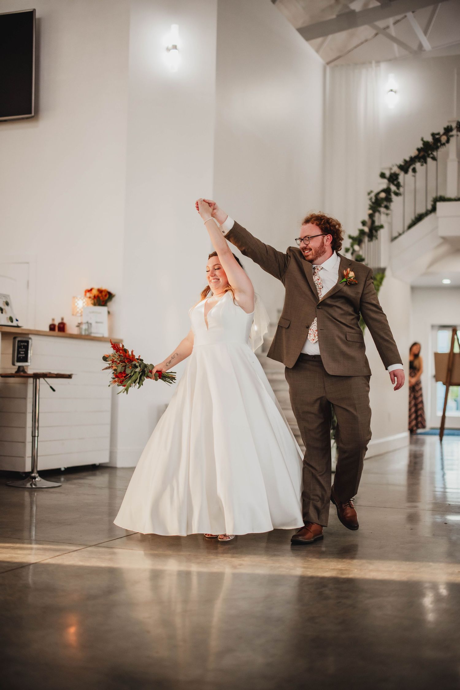 Elegant couple dances together in a modern venue with white walls and polished concrete floors.