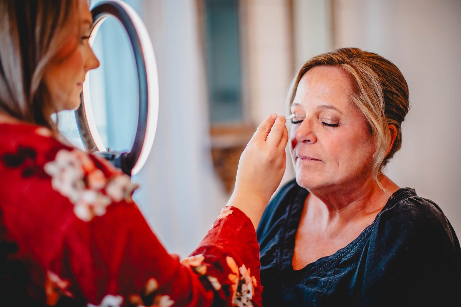 Makeup application being done in front of a round mirror.
