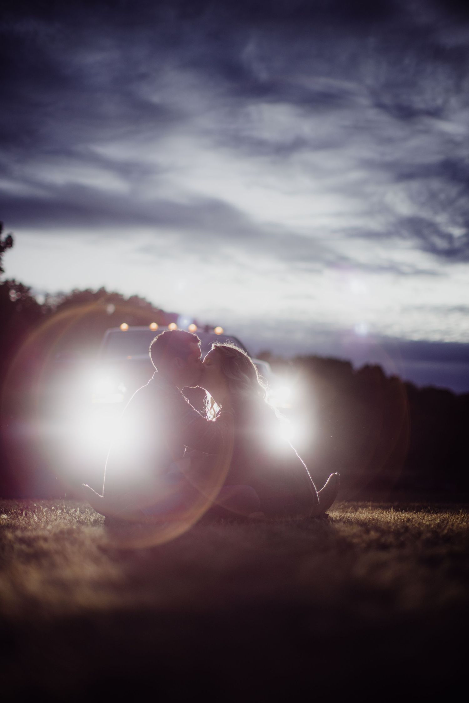 Artistic silhouette portrait of a couple surrounded by bokeh light effects at dusk.