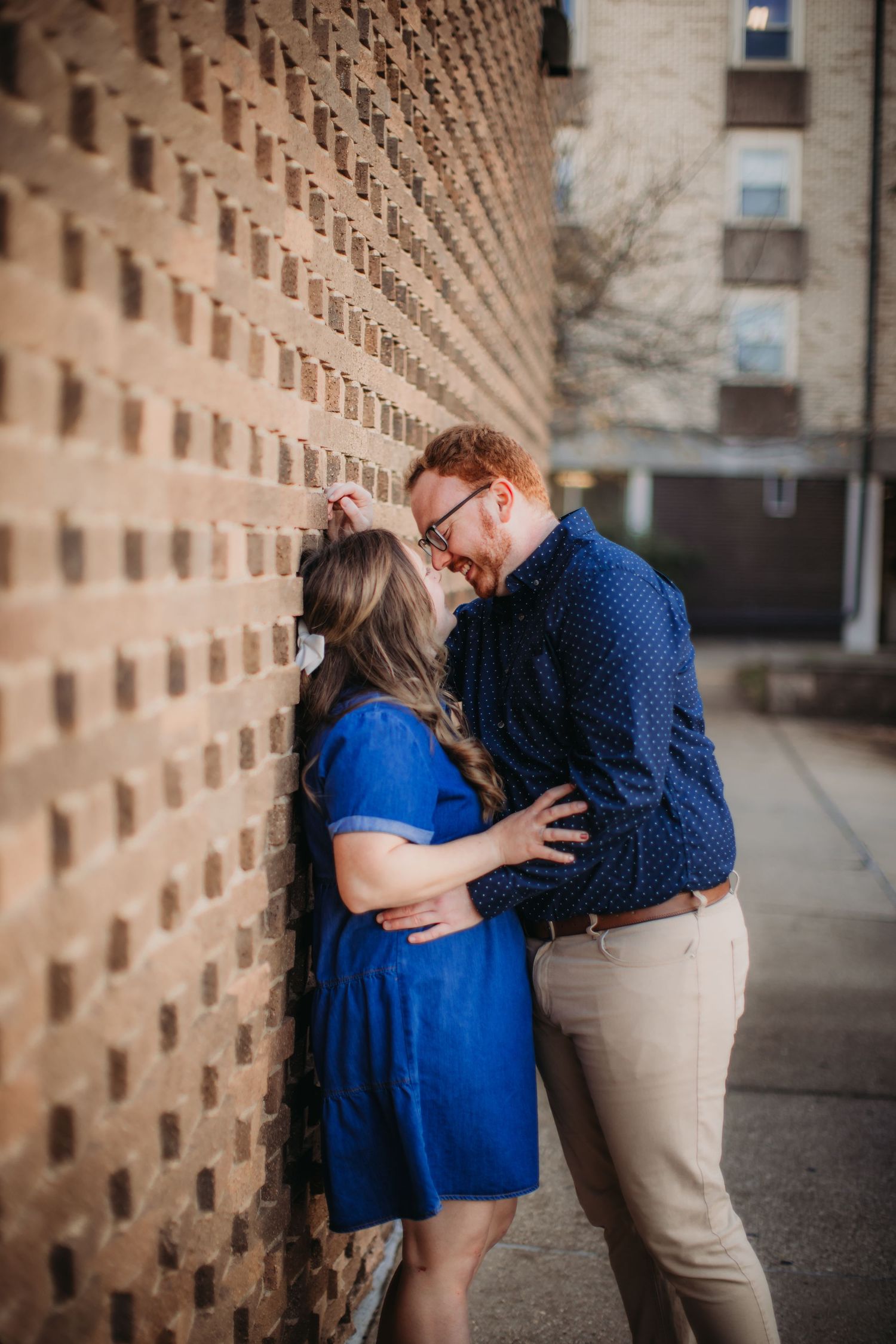 Tender moment captured between a couple by a textured wall.