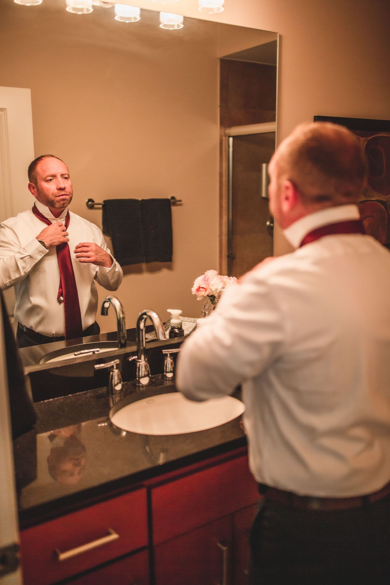 Person adjusting formal attire in bathroom mirror before event.
