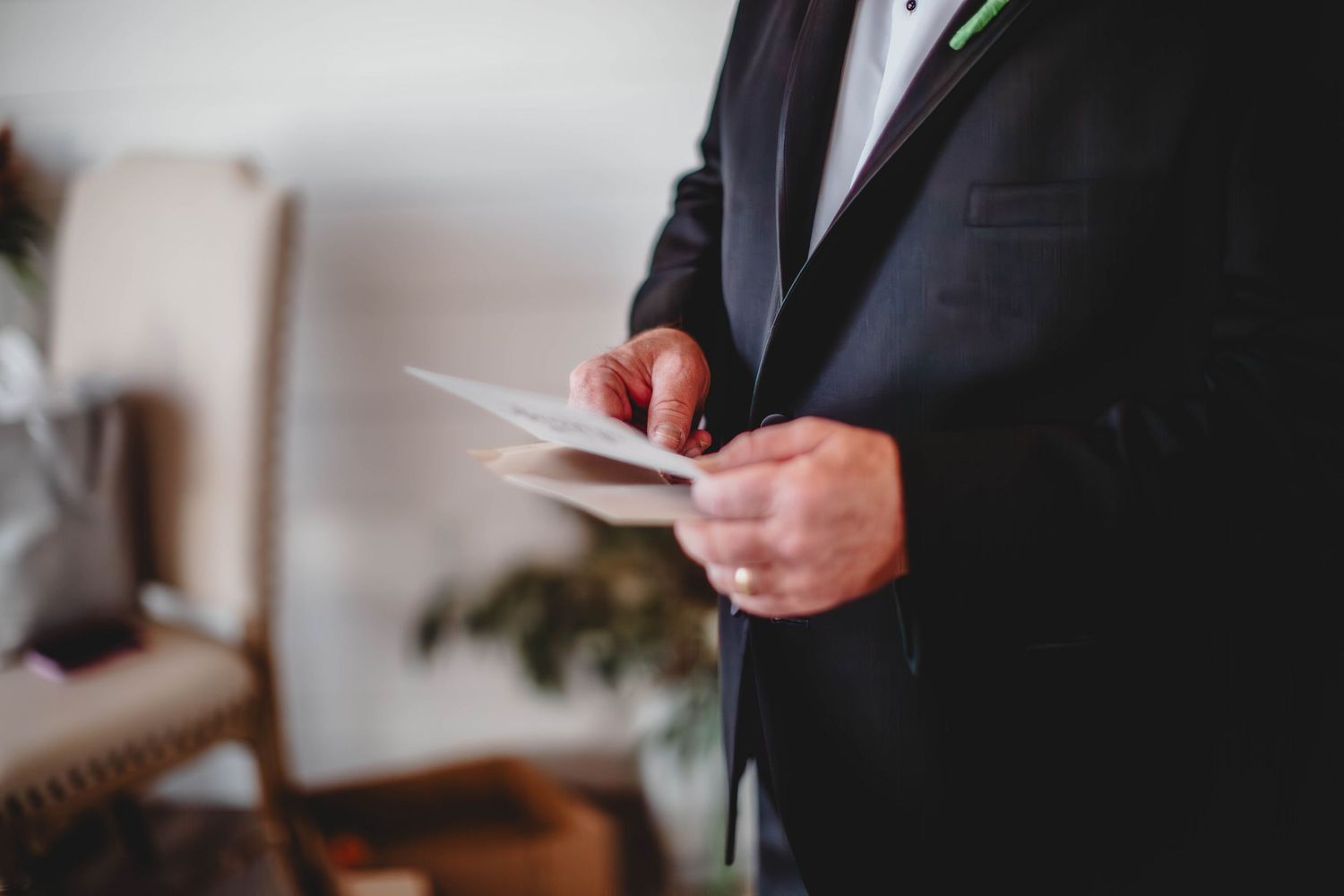 Close-up of hands holding wedding ceremony papers in formal attire.