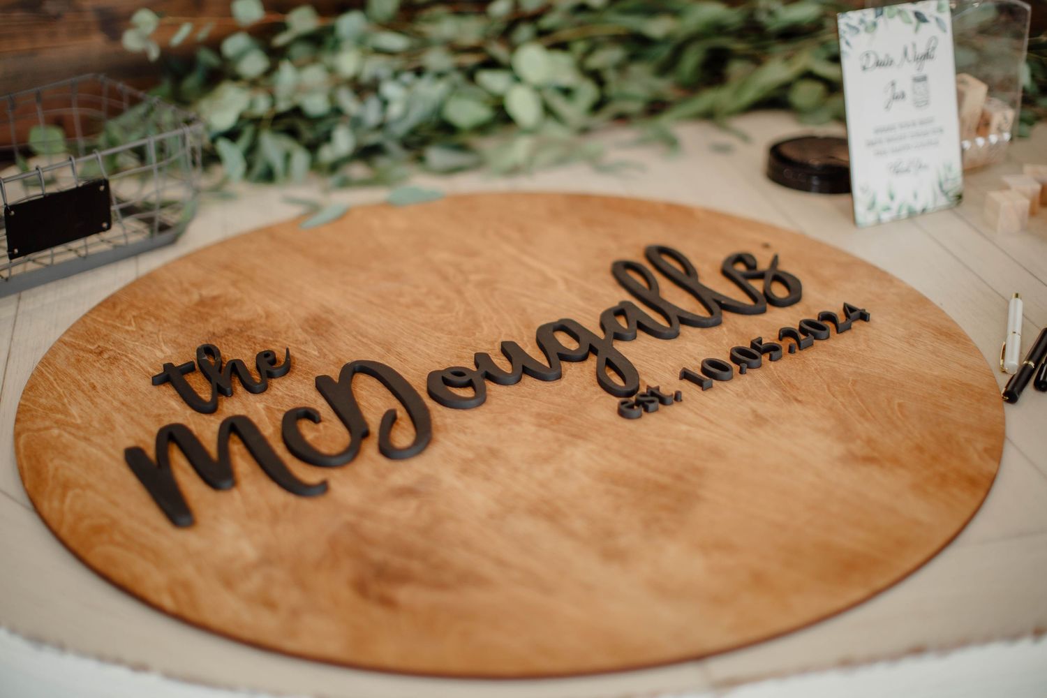 Wooden circular sign with 'The McDougalls' text engraved on its surface.