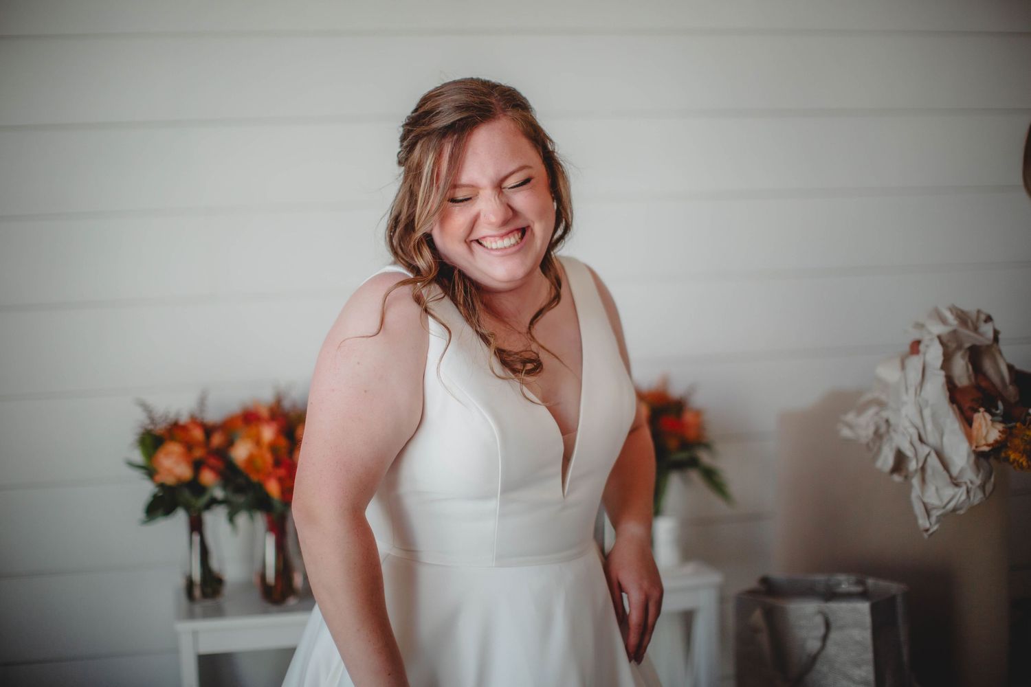 A joyful moment captured in a white-walled room with orange floral arrangements.