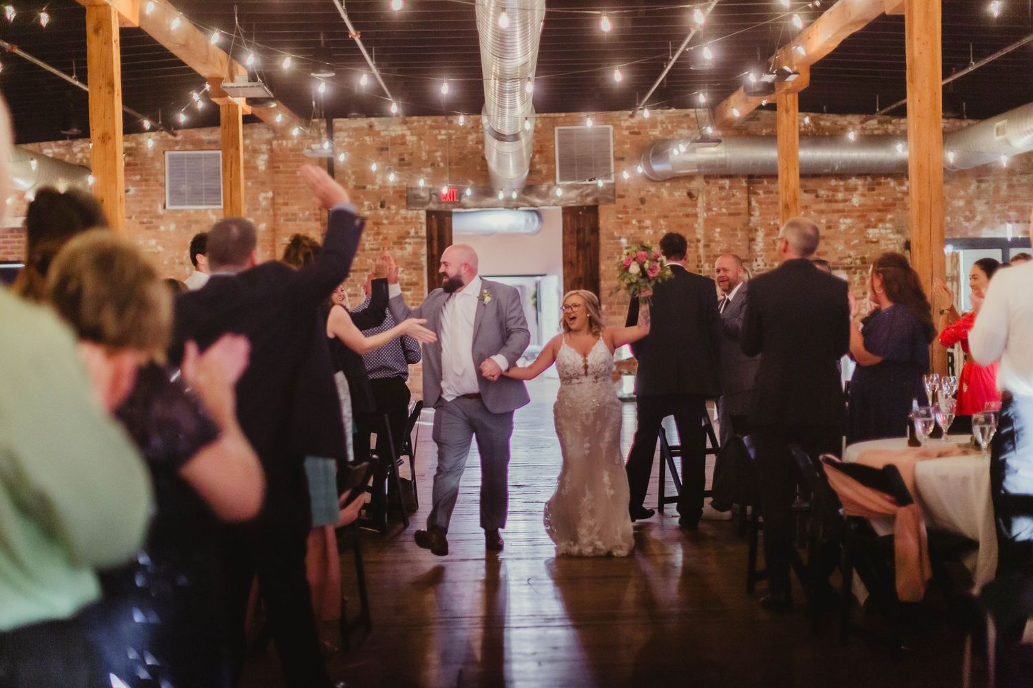Wedding reception venue with exposed brick walls and string lights creating a romantic atmosphere.