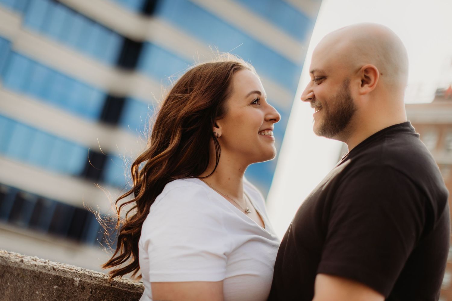 A couple embraces and smiles during a rooftop photoshoot.