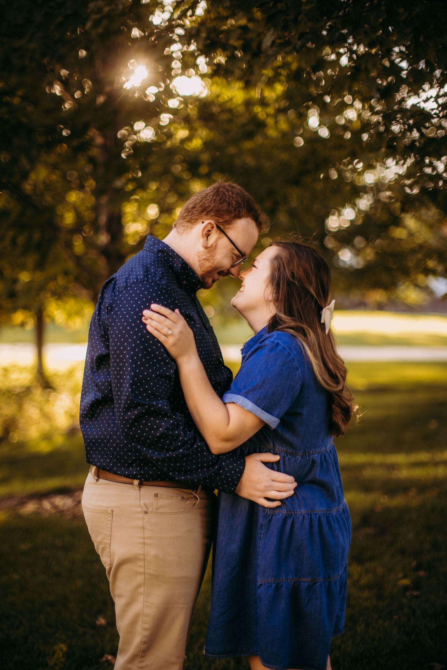 Sweet outdoor photoshoot moment with sun flare through autumn trees.