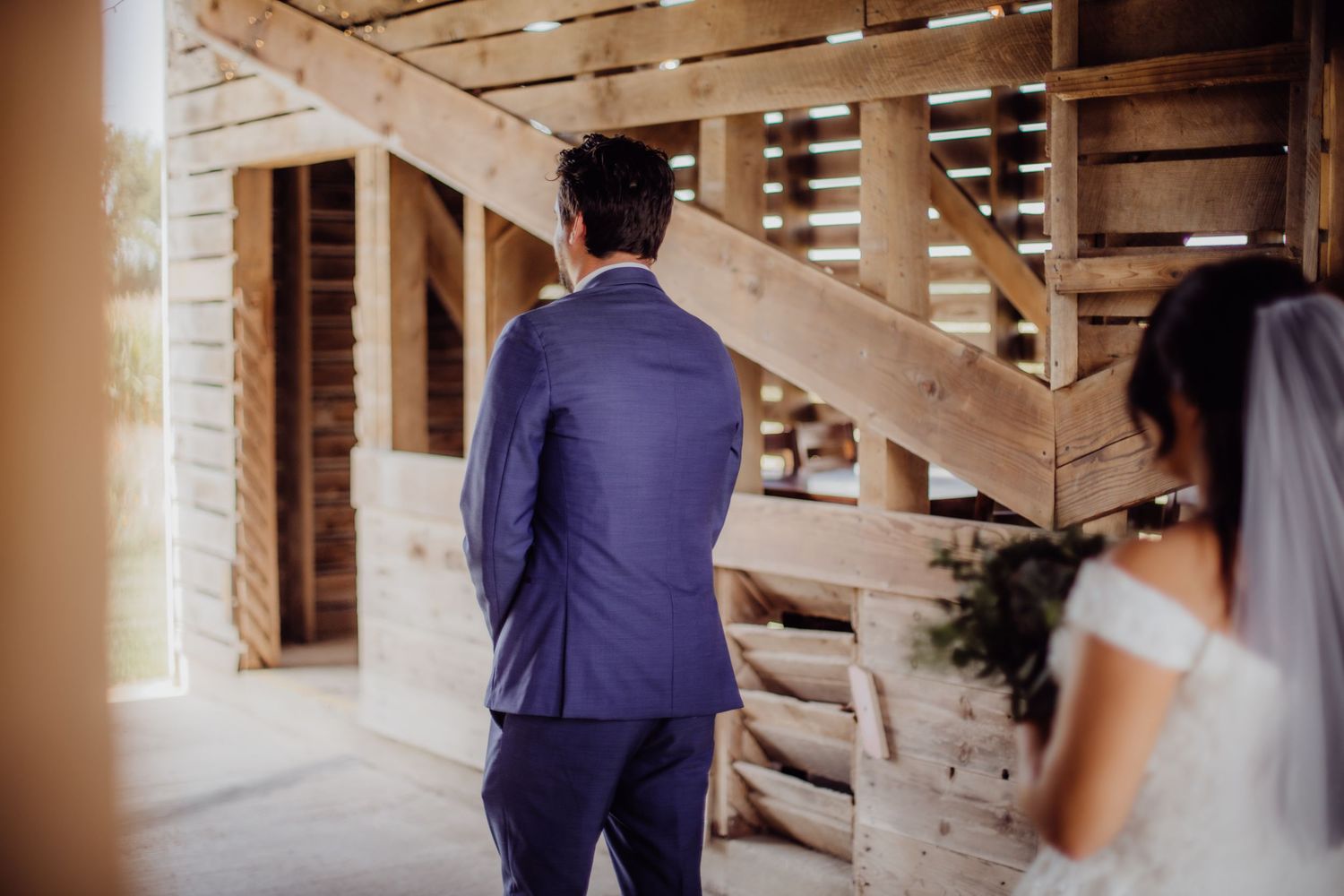 A couple sharing a private first look moment in a rustic barn setting with natural light.