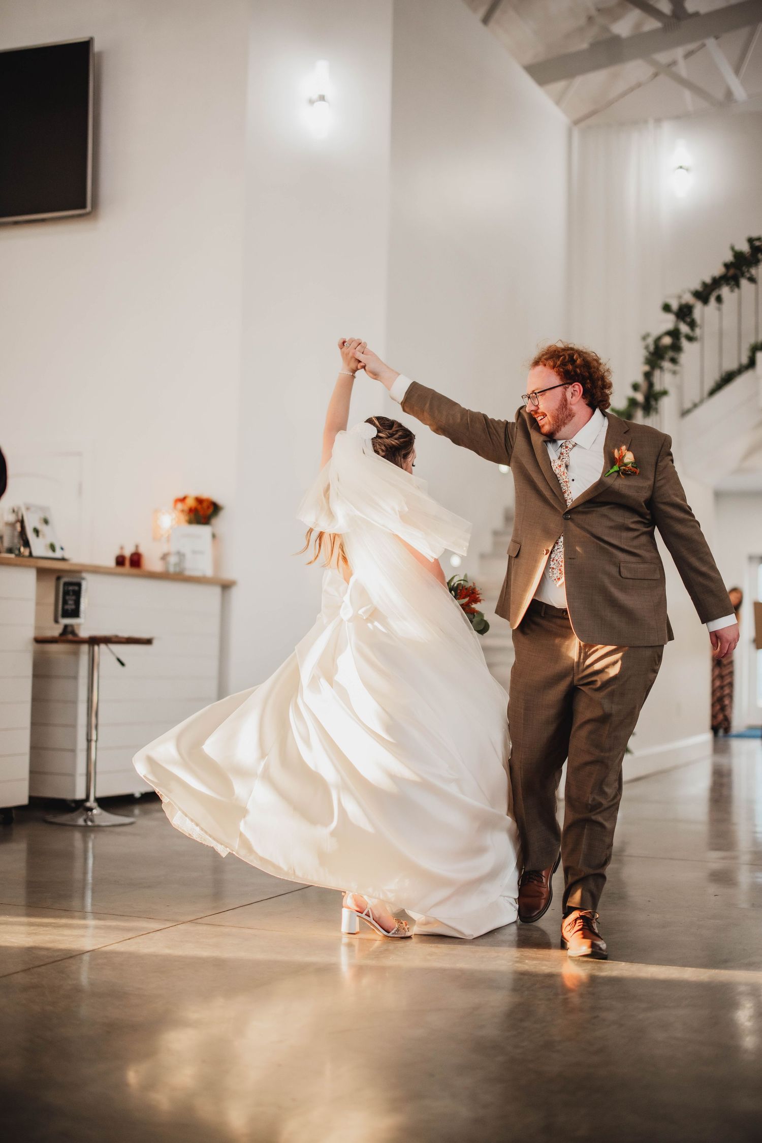 Dynamic shot of newlyweds dancing, with the bride's dress flowing during an elegant spin move.