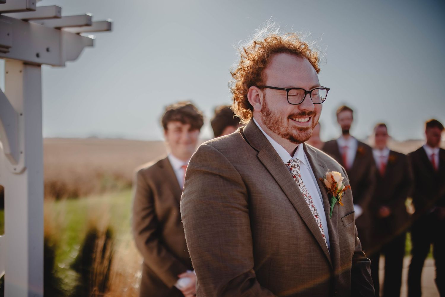 Outdoor wedding ceremony under white pergola with rolling hills in background.
