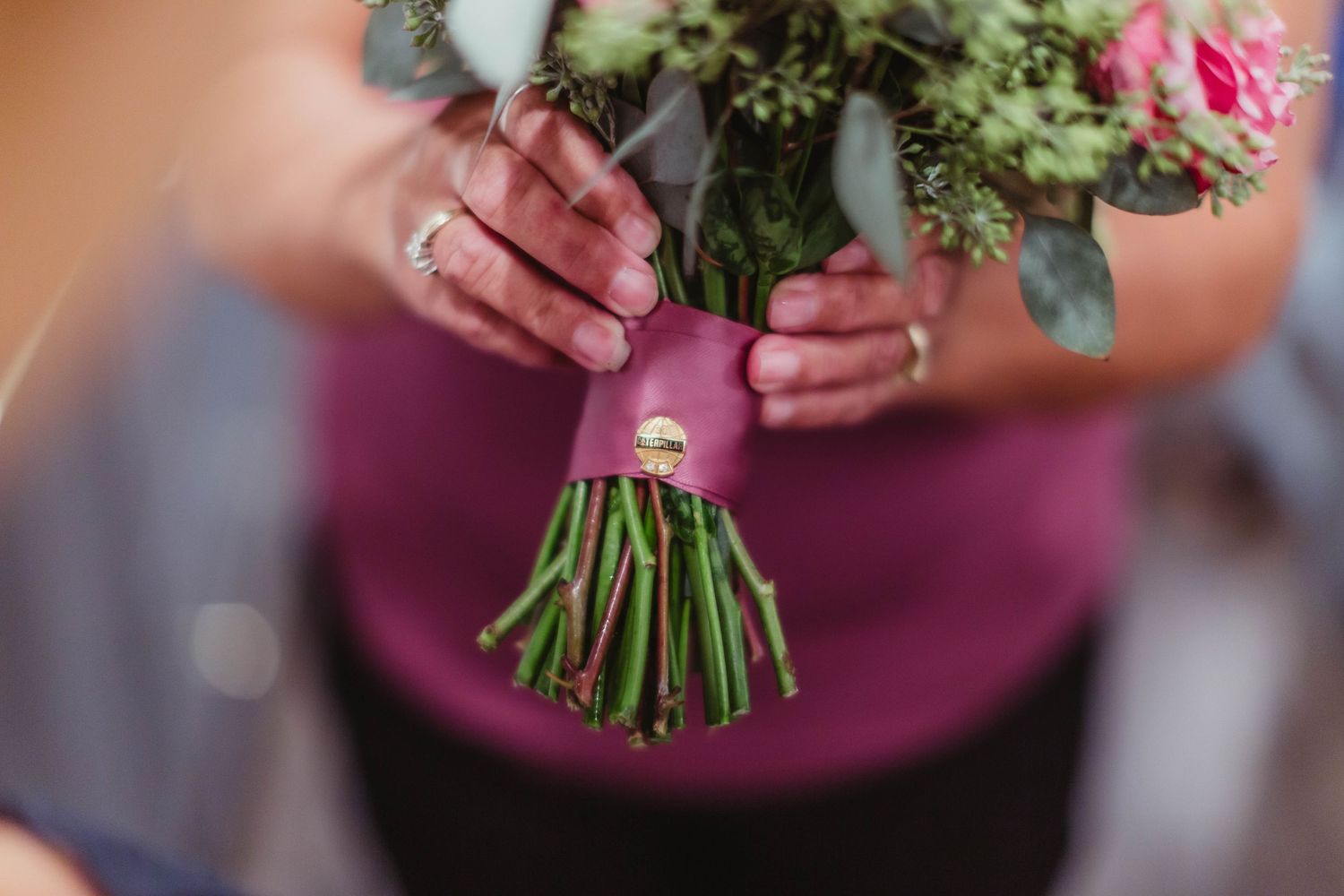 Detail shot of wedding bouquet with pink roses and greenery.
