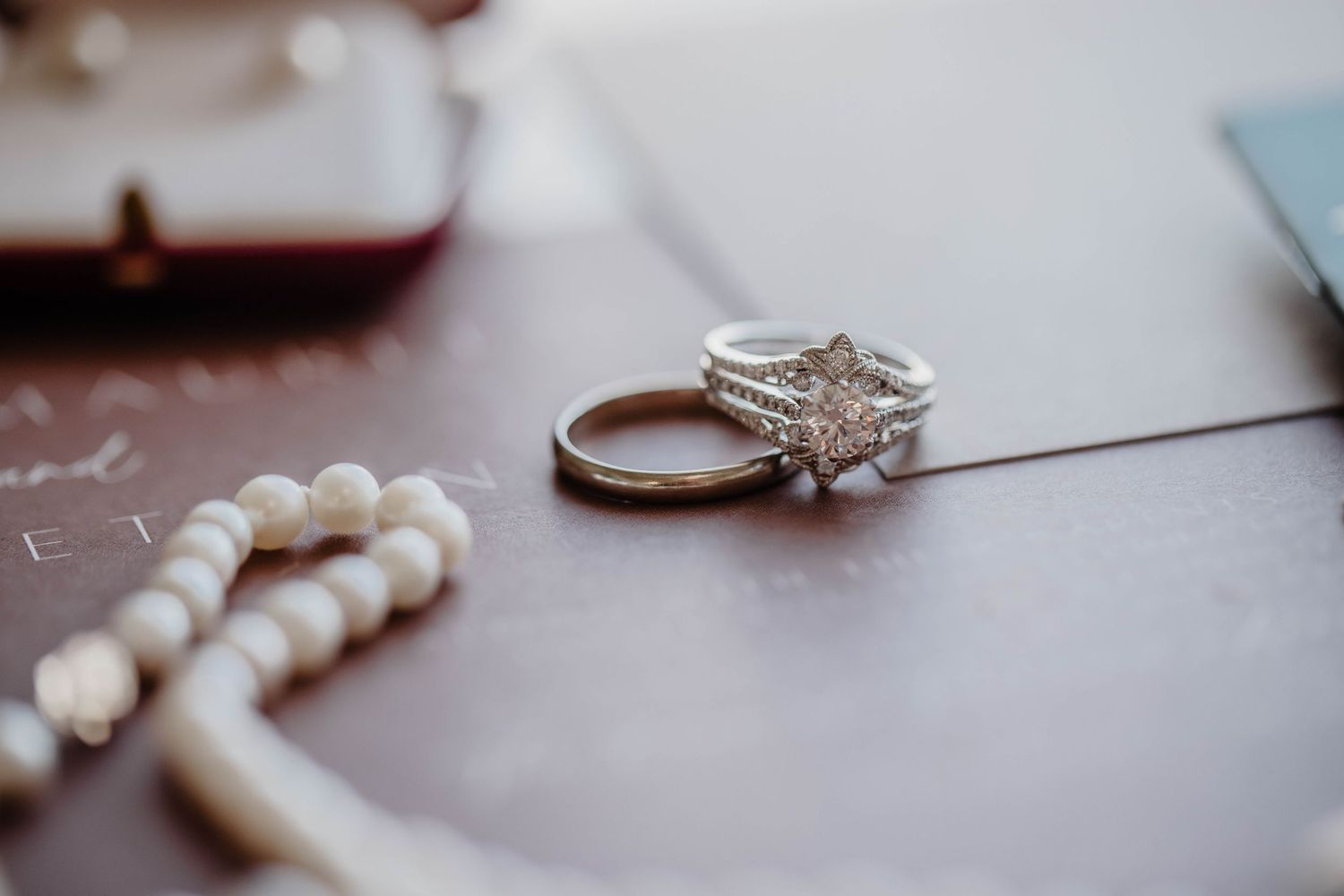 A sparkling diamond engagement ring displayed next to a pearl bracelet.