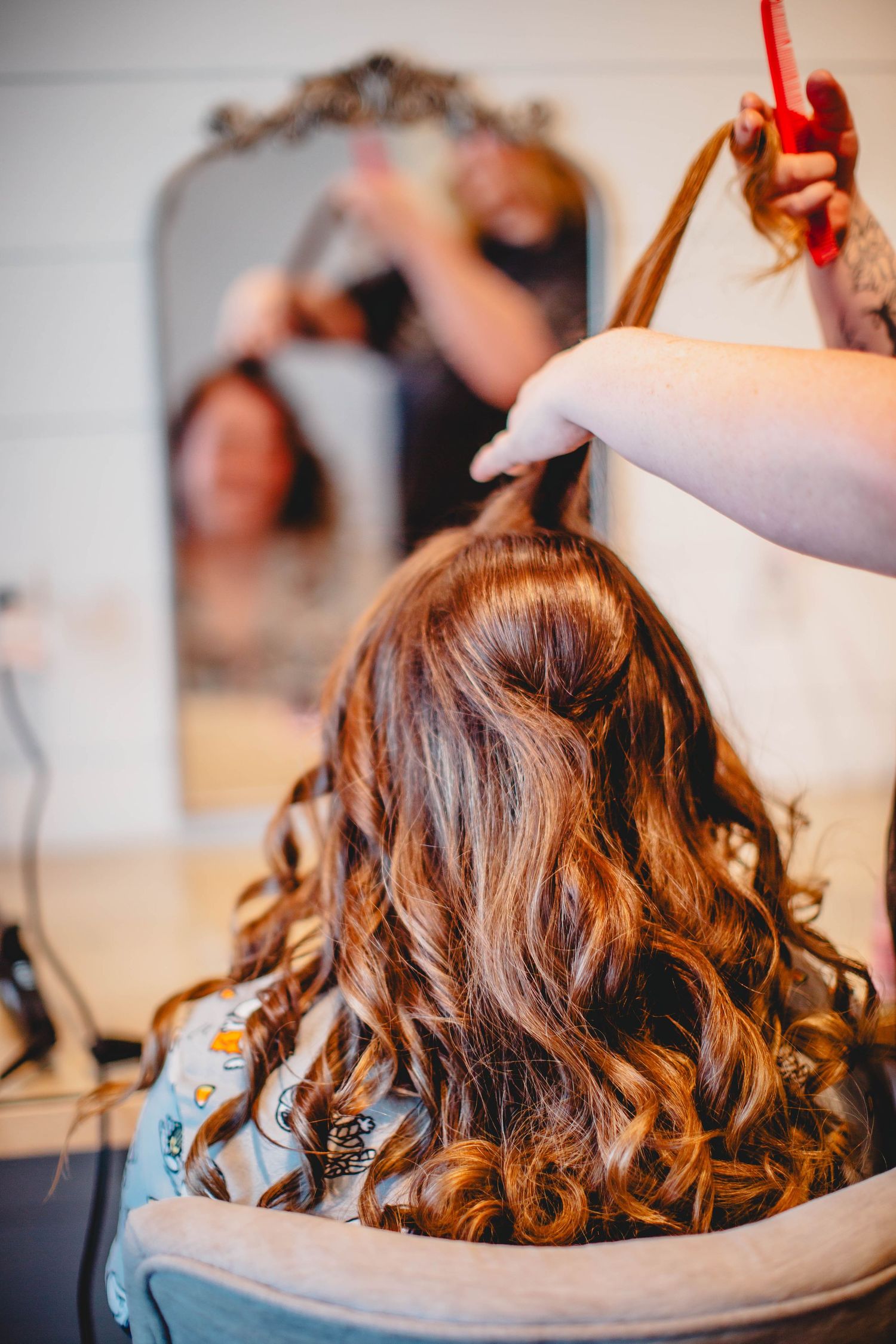 Professional hair styling in progress showing beautiful curls being created.