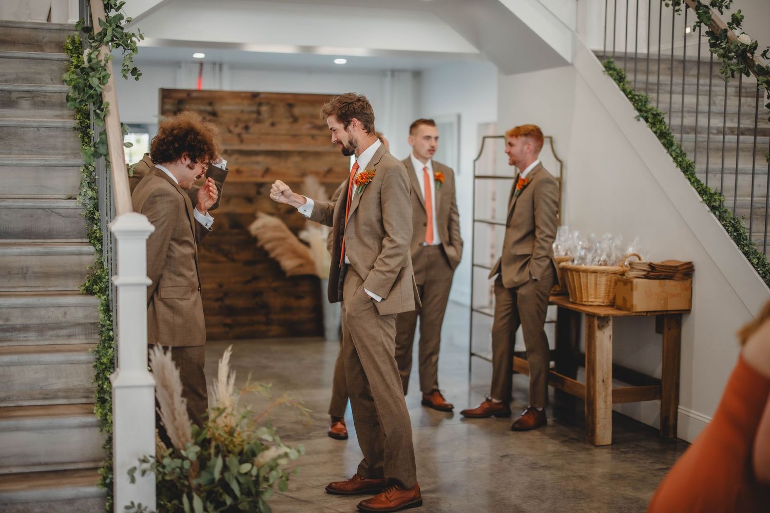 Group of men in suits chatting in a rustic indoor venue with wooden features.