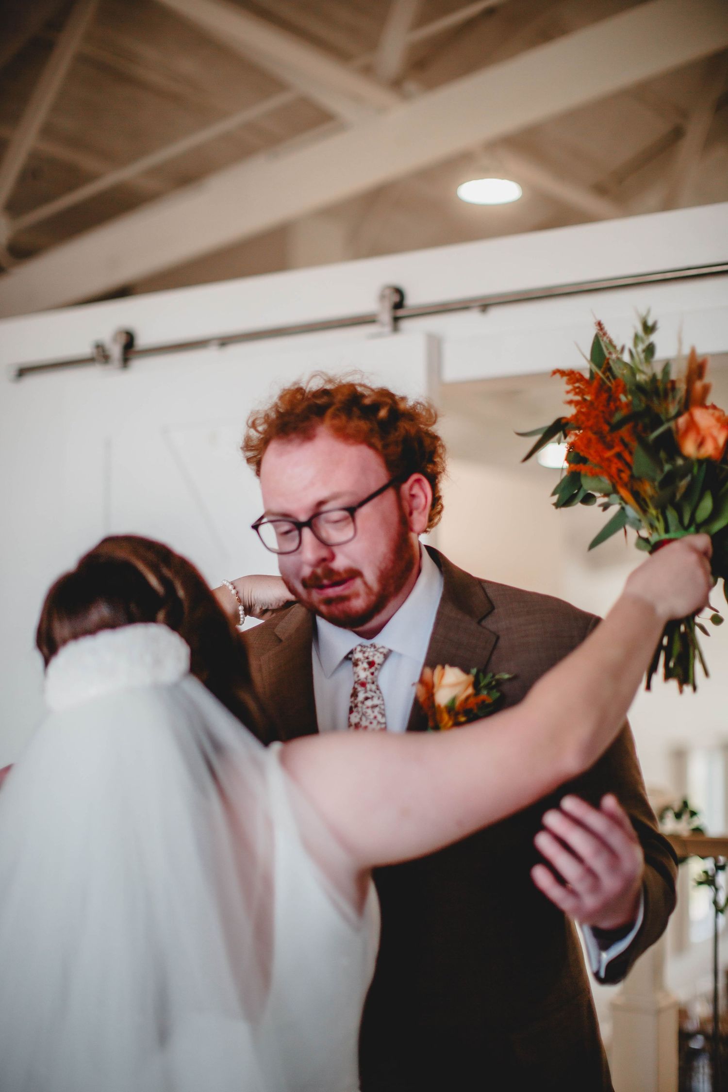 Romantic first look exchange between newlyweds with rustic venue backdrop.