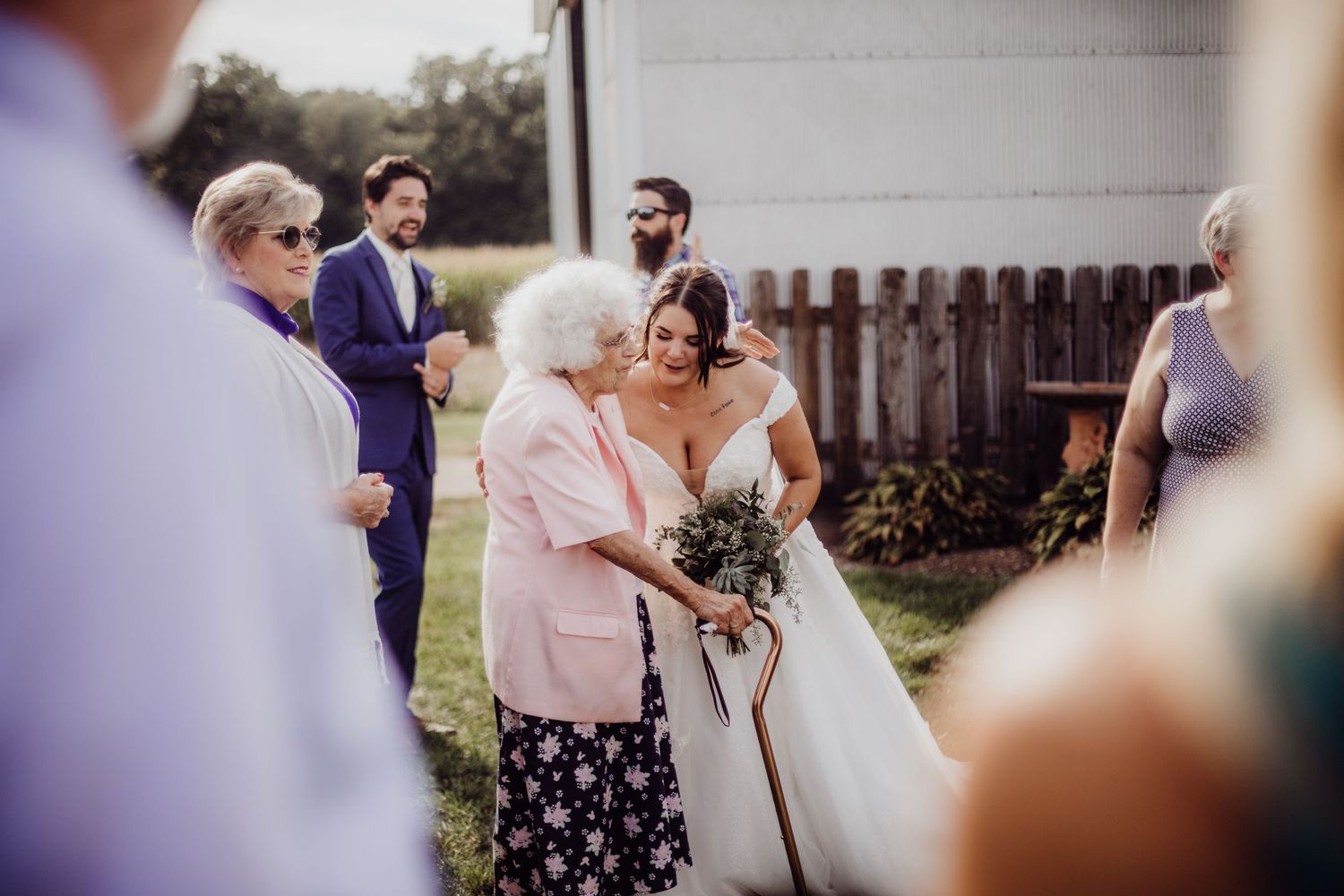 Wedding guests gather outside a white building during an outdoor reception.