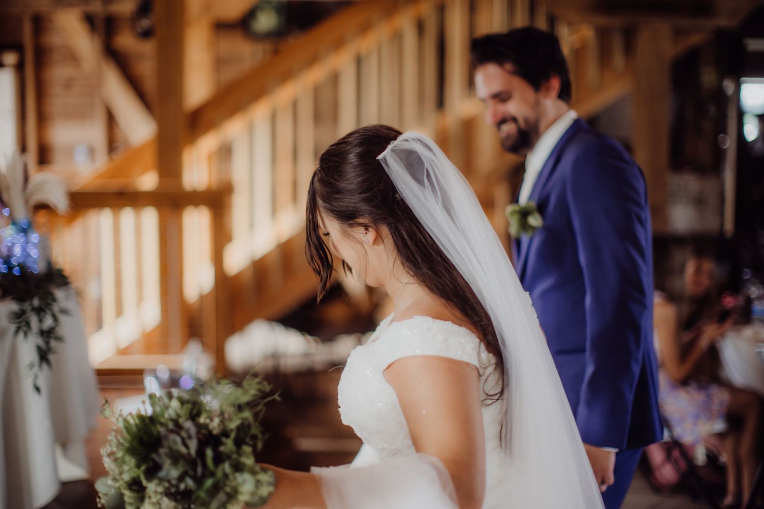Wedding couple shares an intimate moment in rustic barn venue with wooden details.