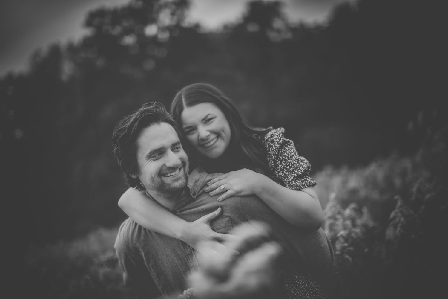 Black and white capture of a couple's joyful embrace in nature.