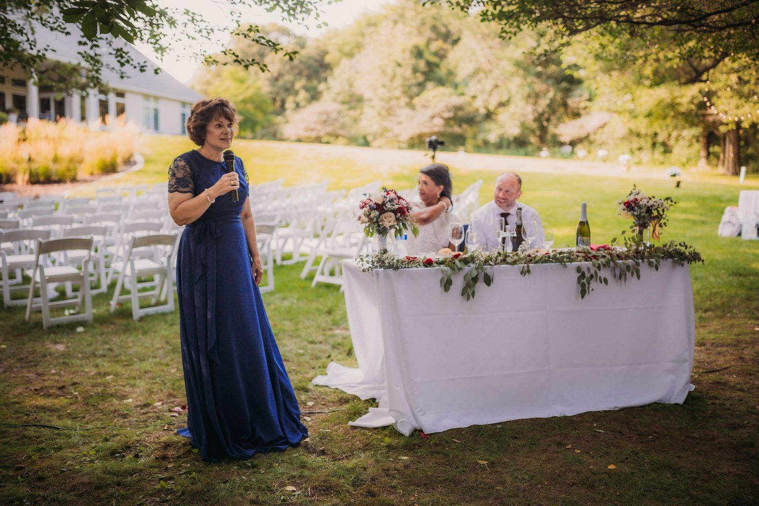 Elegant outdoor wedding reception area with white linens and navy decor elements.