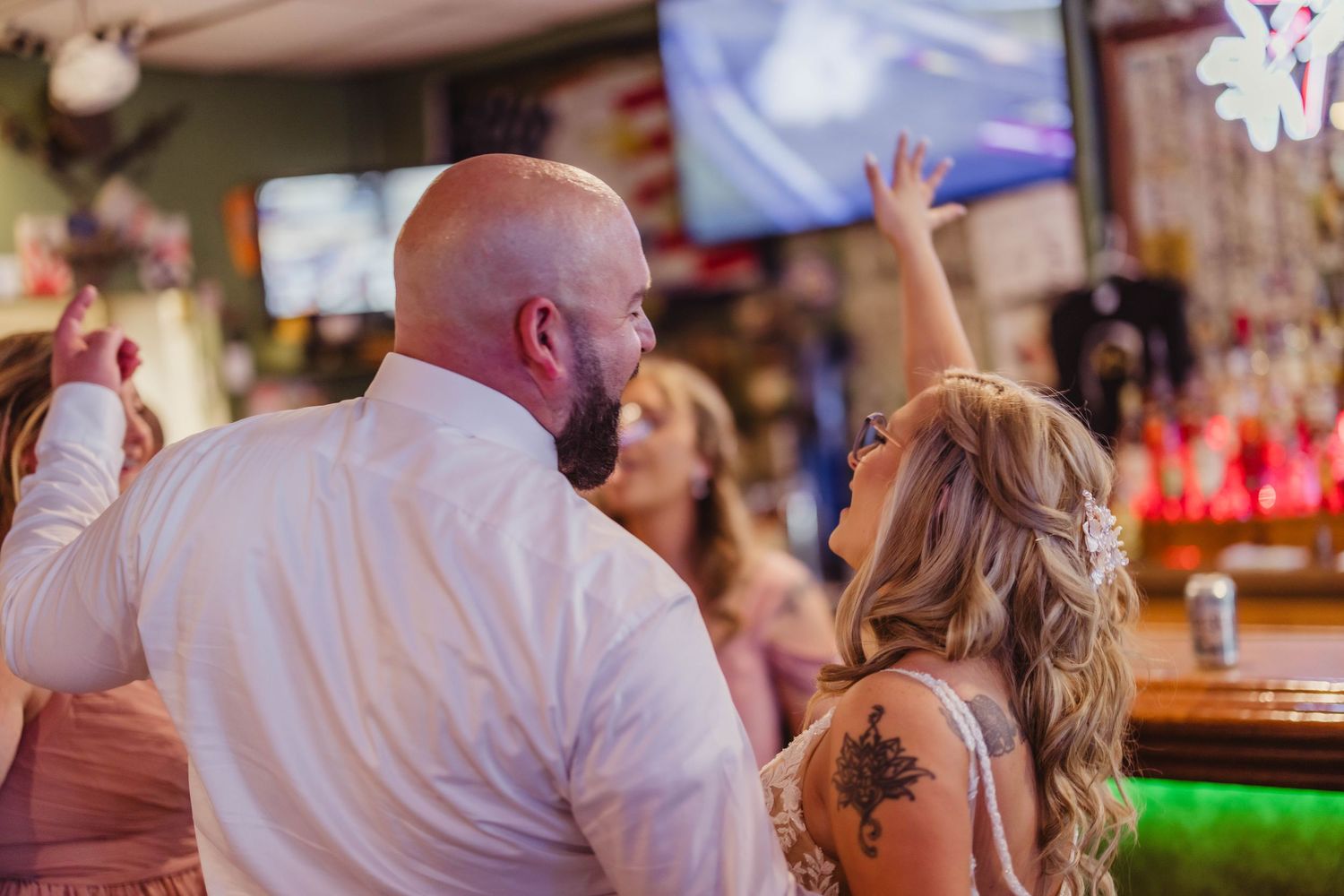 A couple enjoying a fun moment together at a bar with festive lighting in the background.
