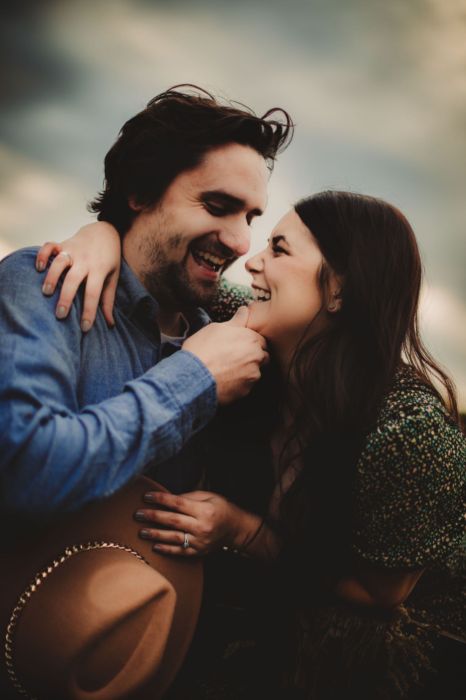 Couple in casual attire sharing genuine laughter during outdoor photoshoot.