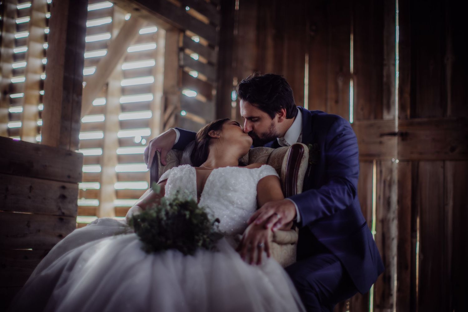 Intimate wedding portrait in a rustic venue with beautiful natural lighting and wooden architecture.