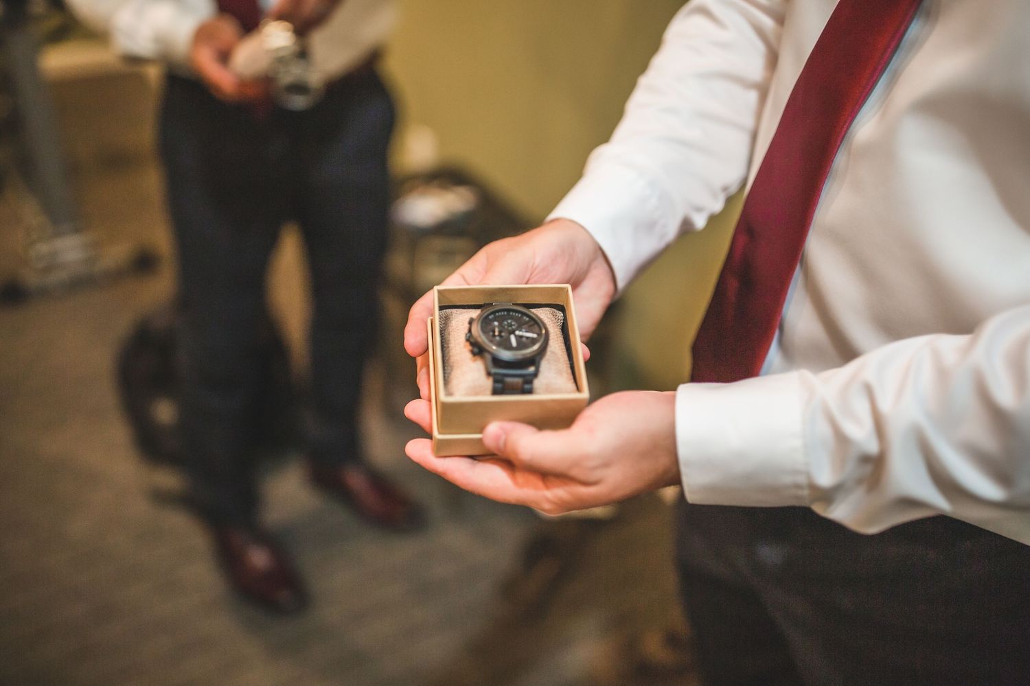 Close up of hands holding small jewelry box during wedding preparations.