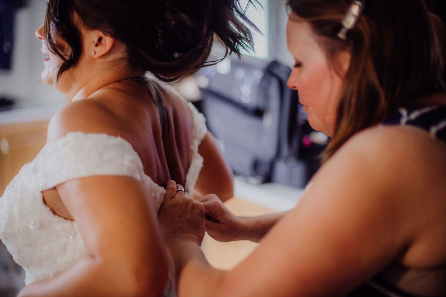 Wedding dress lacing detail being adjusted in soft lighting.