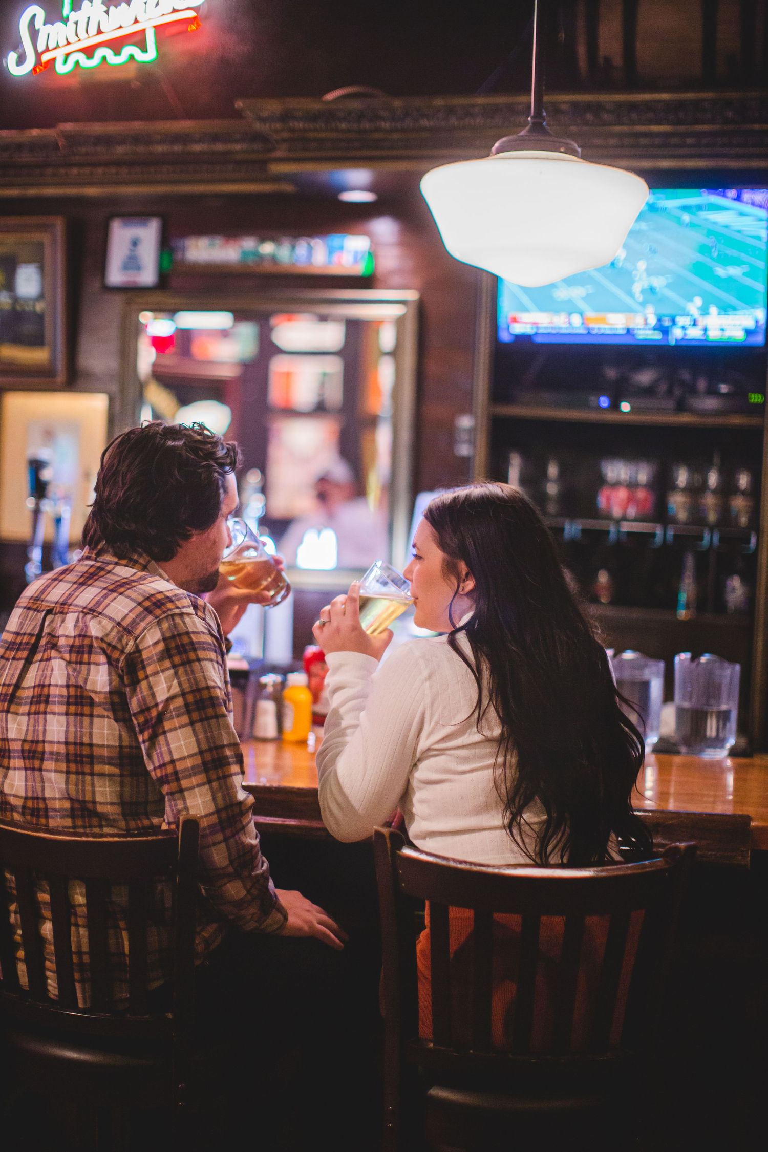 Patrons seated at a bar counter enjoying drinks under ambient lighting.