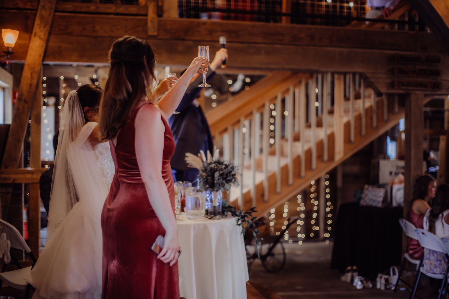 Wedding reception moment captured in rustic barn venue with string lights and wooden details.