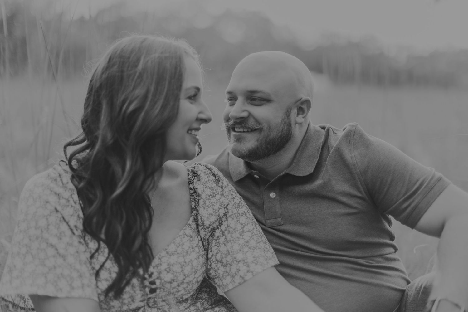 A black and white portrait captures an intimate moment between a couple outdoors.
