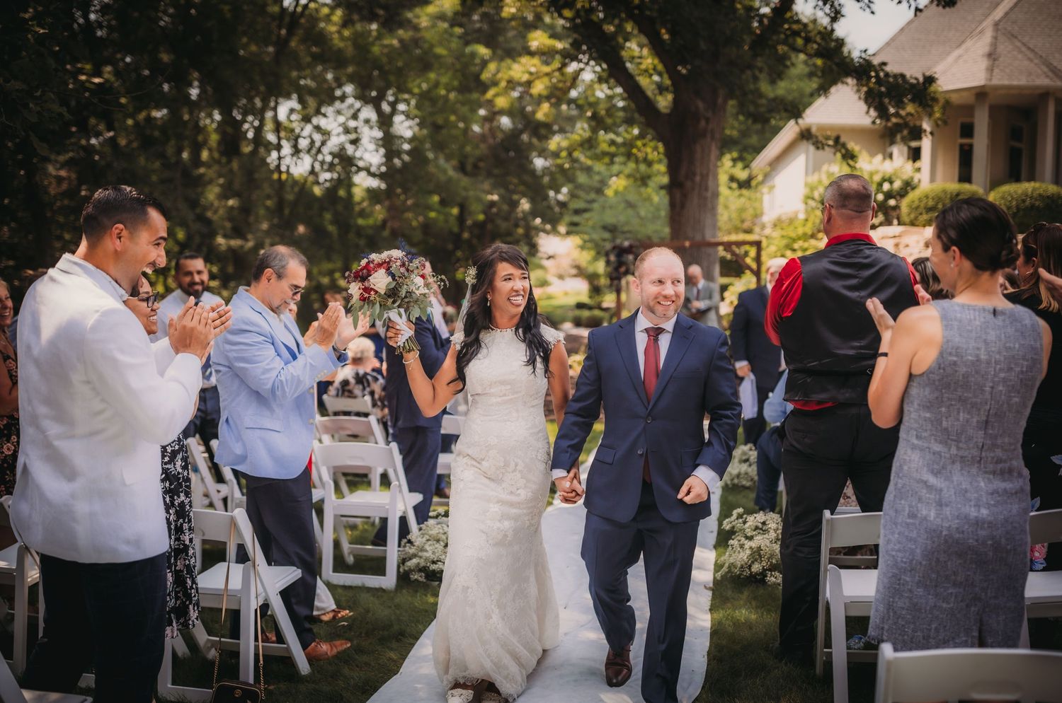 Wedding attendees gather for an outdoor celebration with natural garden backdrop.