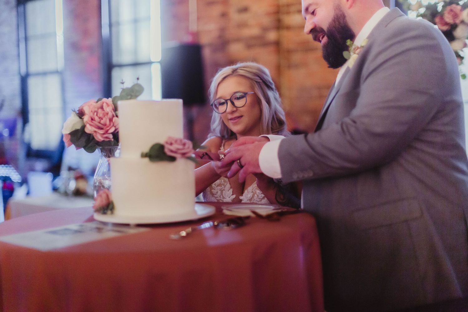 Wedding reception details with cake table and decorations in rustic brick venue.