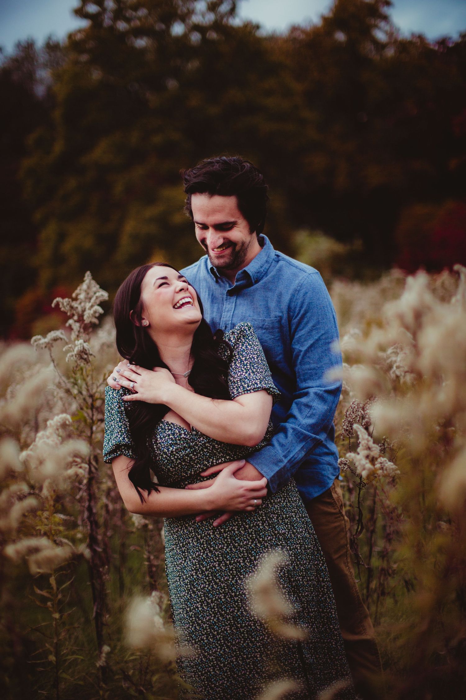 Joyful couple sharing tender moment in field during sunset.