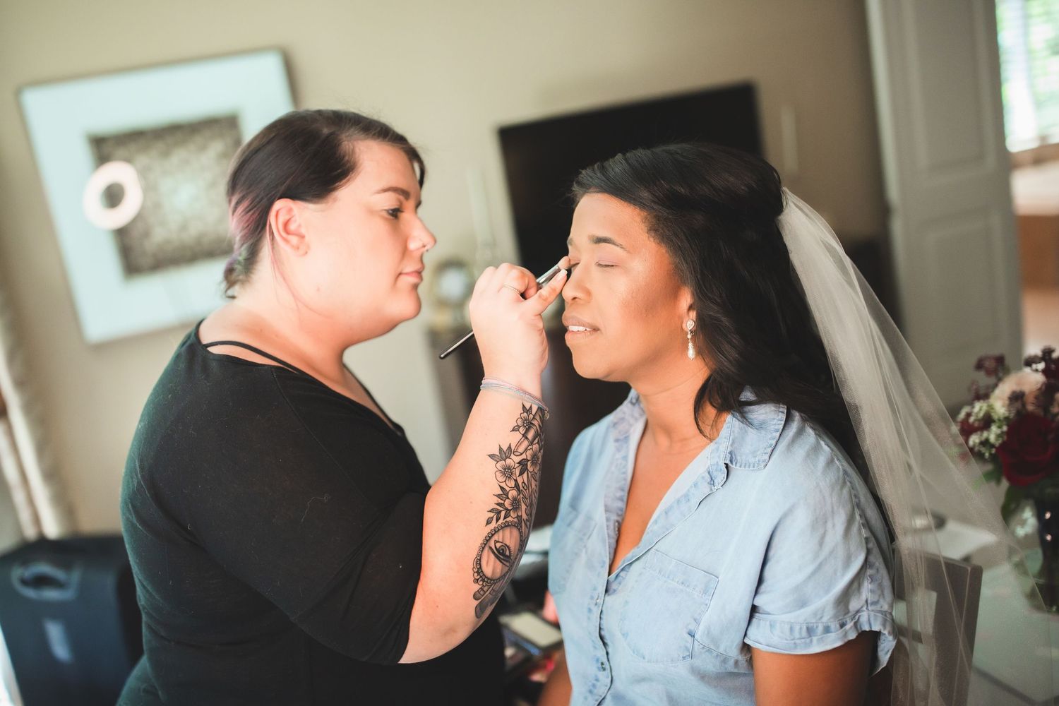 Makeup artist applies cosmetics to bride during wedding preparations.