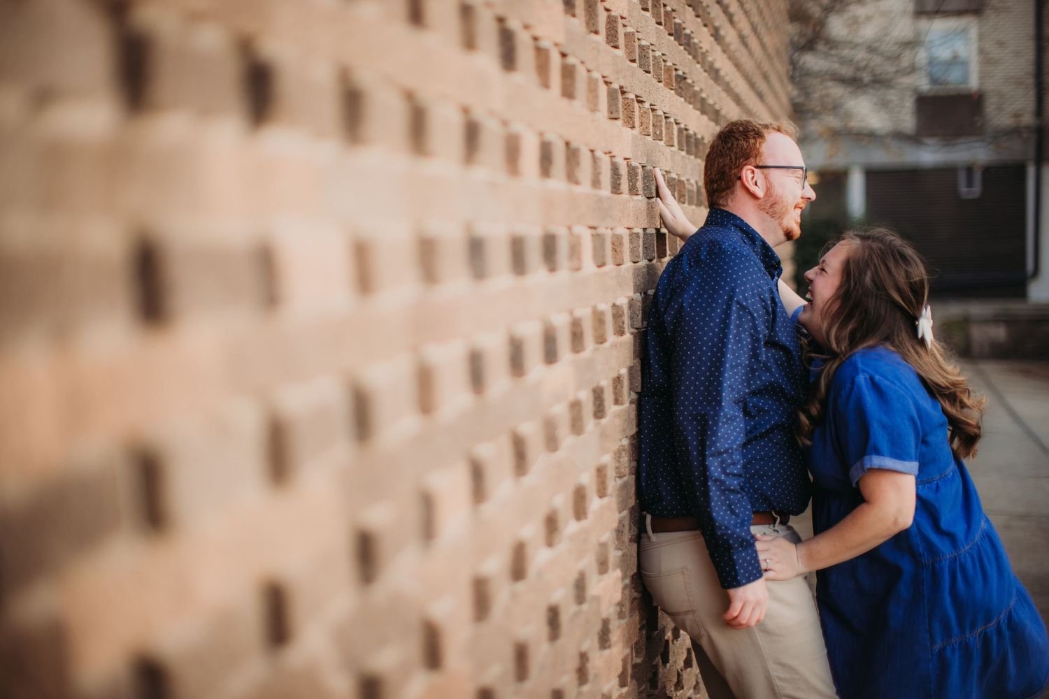 A sweet moment between a couple dressed in blue and khaki against an industrial backdrop.