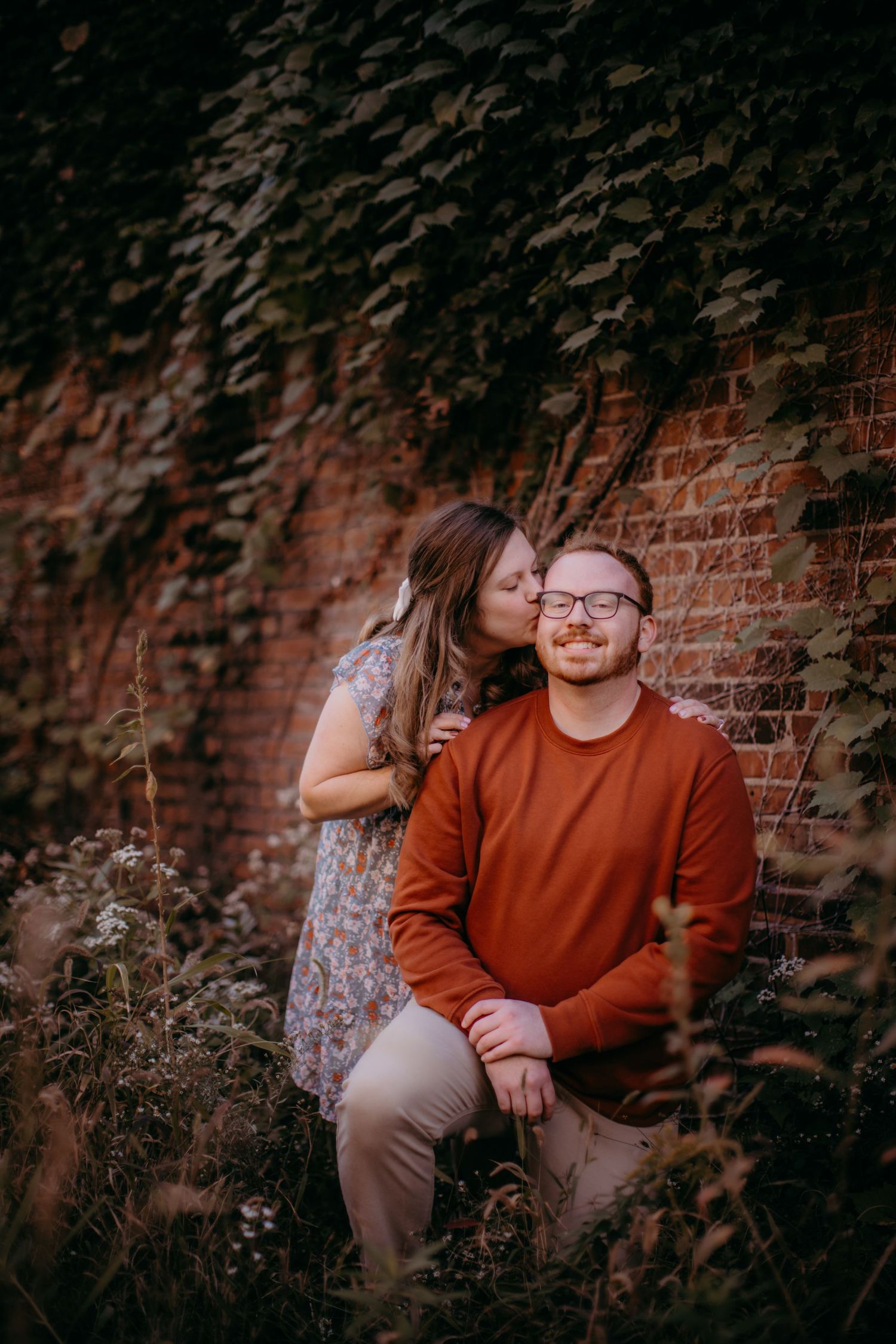 Intimate moment captured during a fall engagement session with rustic backdrop.