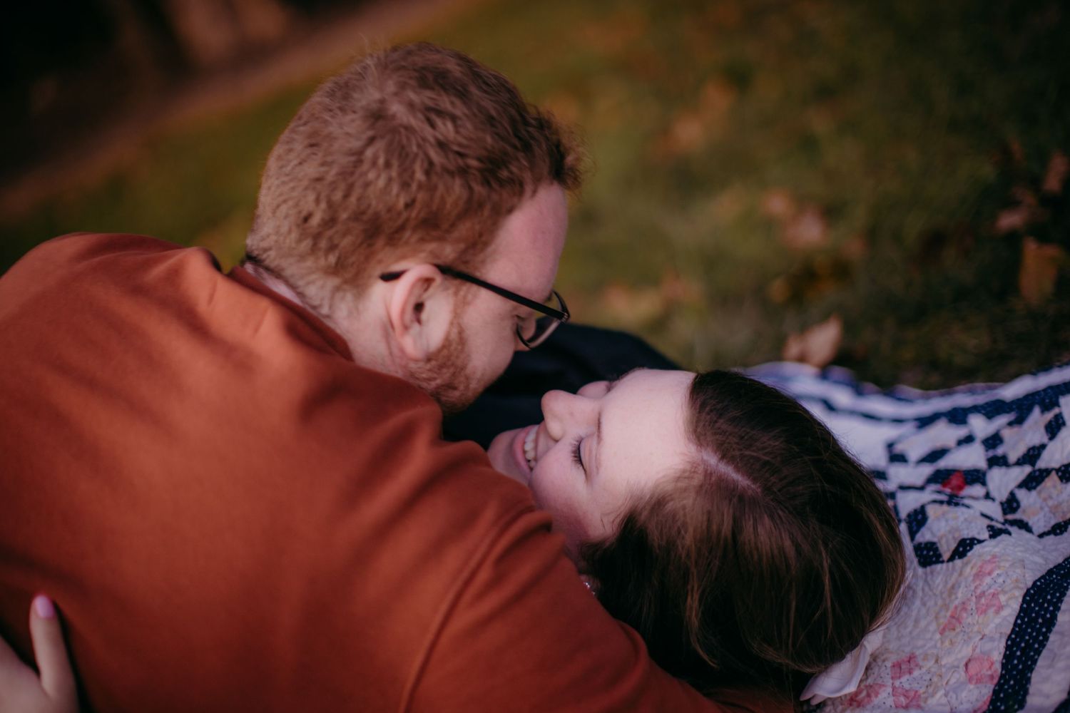 Close-up shot of couple embracing on blanket during outdoor photo session.